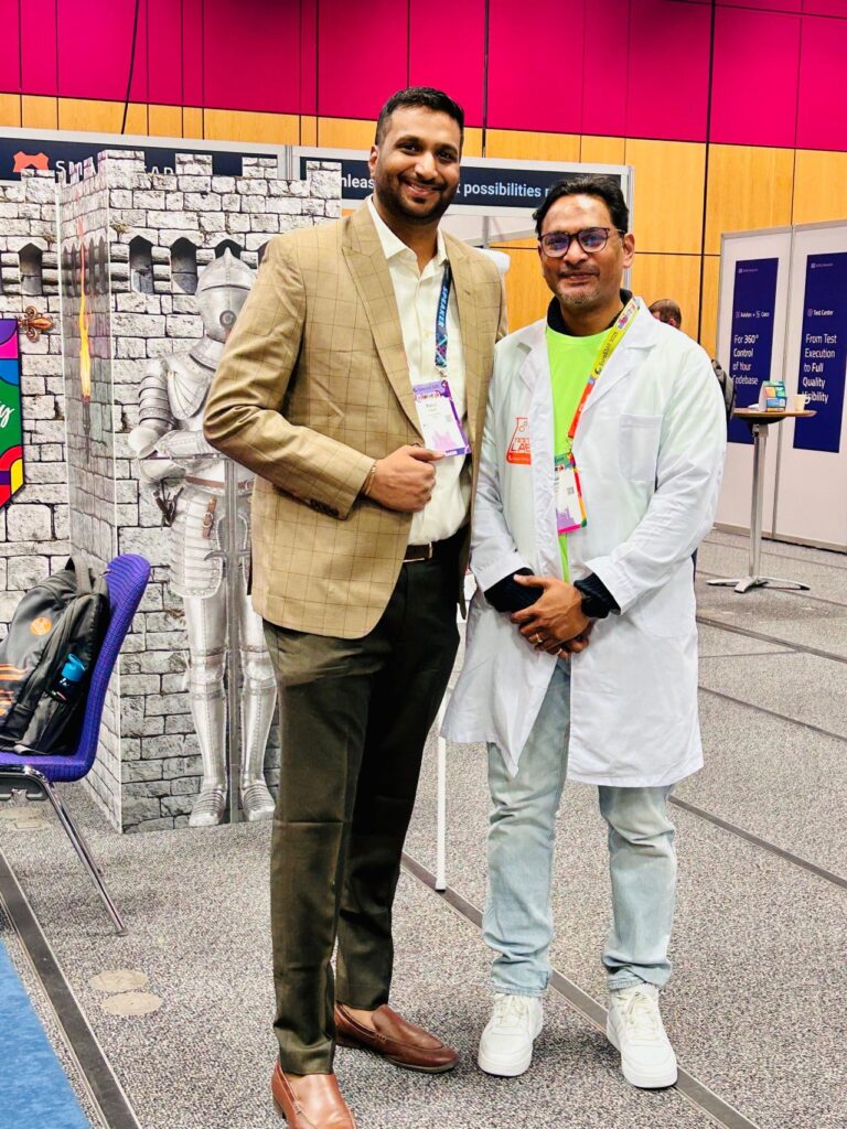 conference attendees posing together, smiling in front of exhibition booths with a castle-themed display and information boards.
