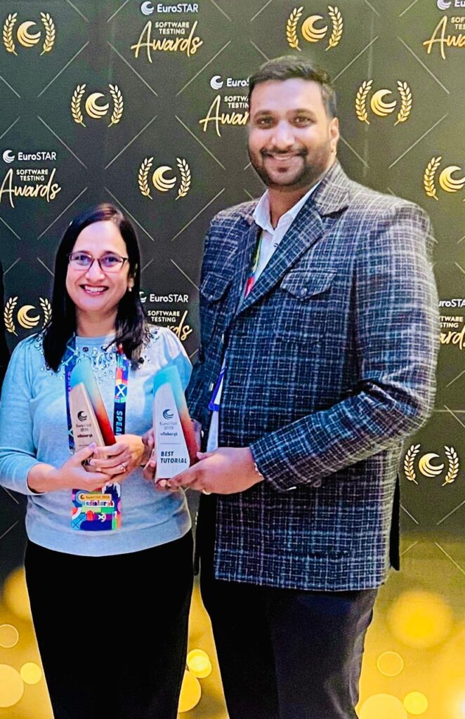 Two people smiling at the EuroSTAR Software Testing Awards event, holding awards in front of a backdrop displaying the event logo.
